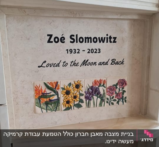 מצבה עם כיתוב ואריחי פרחים צבעוניים